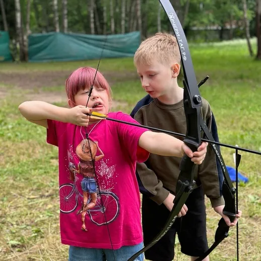 Дети учатся стрелять из лука на тренировке на свежем воздухе