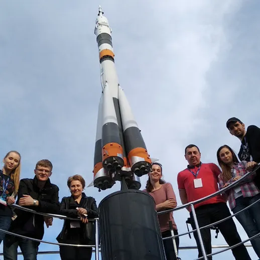 Группа людей вокруг ракеты на выставке в космическом центре, солнечный день, экскурсия по космонавтике