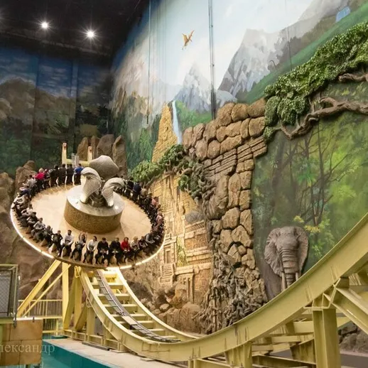 Аттракцион в крытом парке развлечений с круговым движением в окружении экзотической природы