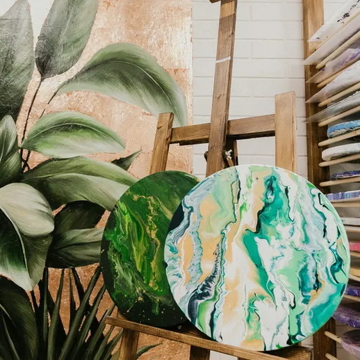 Яркие абстрактные картины на мольберте в художественной студии среди зелёных растений