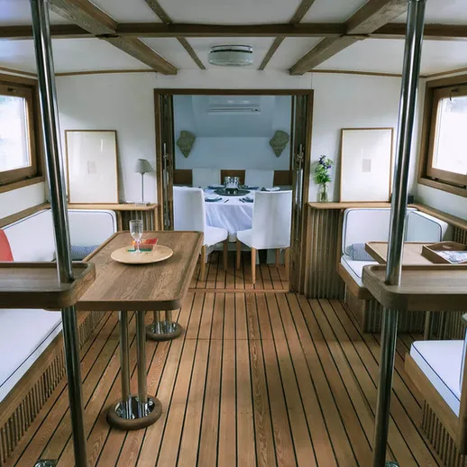 Уютный интерьер на яхте с деревянным полом и обеденным столом в центре вечернее время