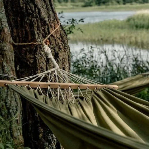 Гамак, натянутый между деревьями у озера, идеальное место для отдыха на природе в солнечный день