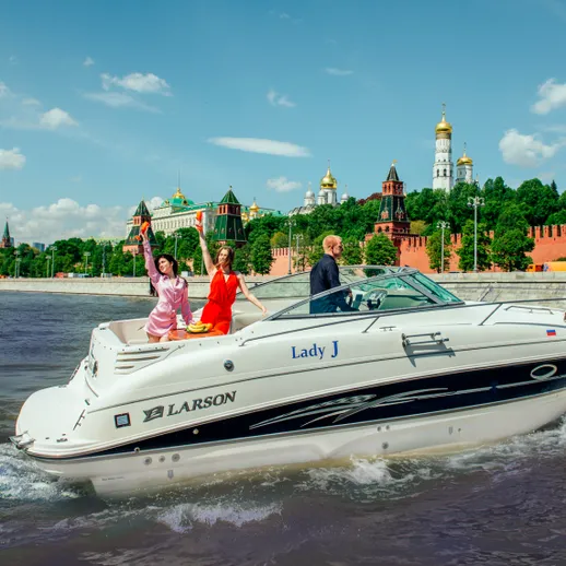 На реке в Москве три человека на лодке рядом с Кремлём
