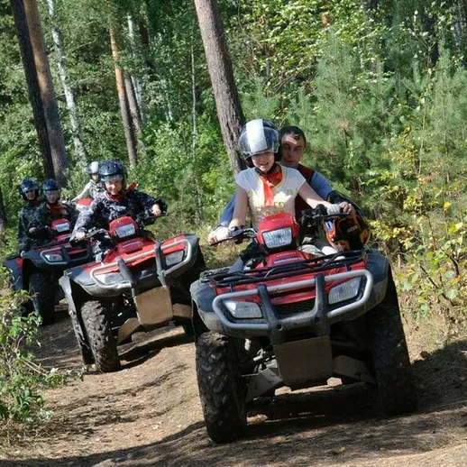 Взрослые и дети на квадроциклами в лесу, наслаждаясь активным отдыхом и приключениями в живописной местности