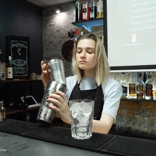 Молодой бармен готовит коктейль в стильном баре в вечернее время