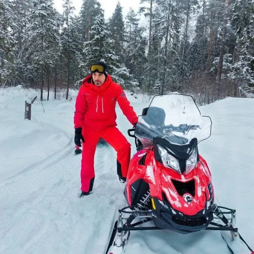 Мужчина на снегоходе в зимнем лесу, наслаждается природой и отдыхом