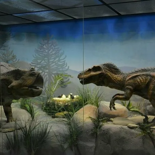 Два динозавра в натуральную величину в музейной экспозиции с природным ландшафтом