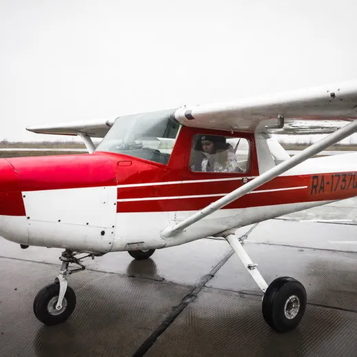Малый самолет с красными полосами на аэродроме в облачную погоду, готовится к взлету