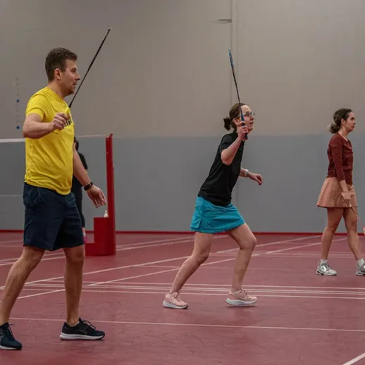 Игроки в бадминтон на тренировке в спортивном зале в вечернее время