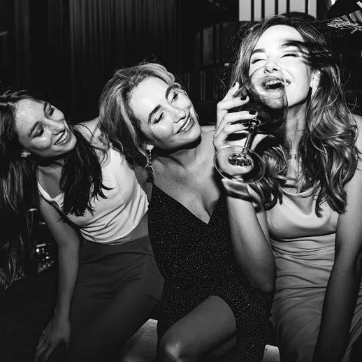 Подруги веселятся на вечеринке с коктейлями на фоне вечернего города