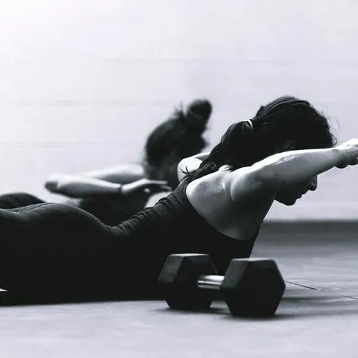 Женщины занимаются фитнесом в спортзале, выполняя упражнения с гантелями утром