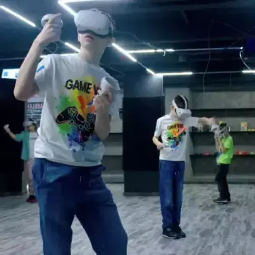 Группа подростков играет в виртуальные игры в игровом центре в вечернее время