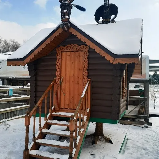 Заброшенная избушка в снегу с фигурами на крыше, зимний день, деревенский пейзаж