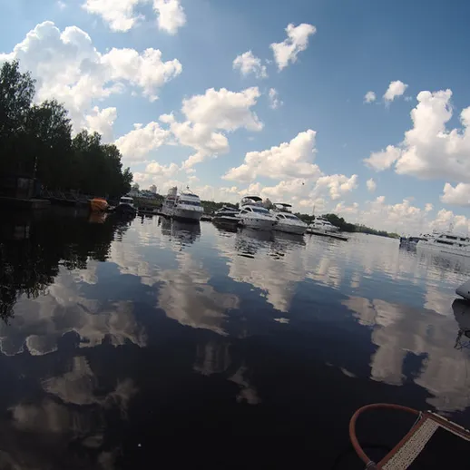 Красивый водный пейзаж с яхтами на спокойной воде под облачным небом в летний день