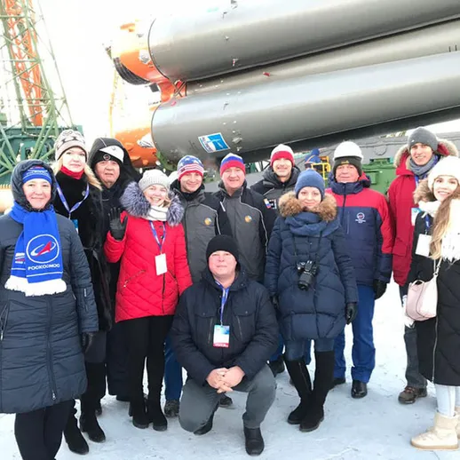 Группа людей на фоне ракетного носителя в зимний день на космодроме в России