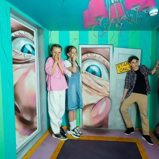 Экспрессивные дети в иллюзии комнаты с 3D-графикой на выставке в Москве, позирующие перед стенами с изображением рук и глаз