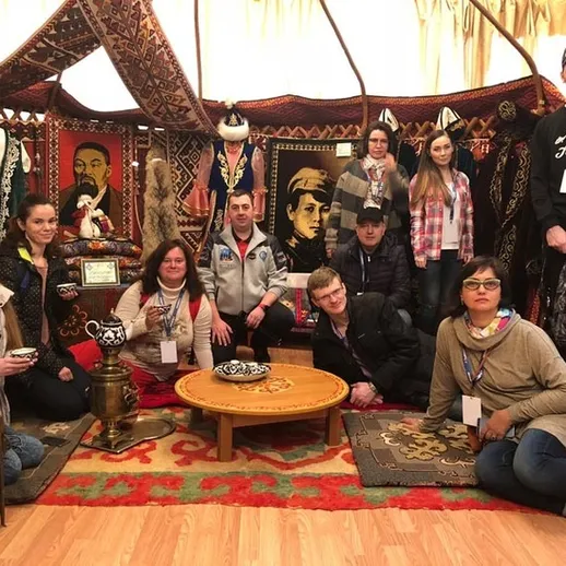 Группа людей у традиционного юрта с национальными узорами и предметами искусства, сделанными в России