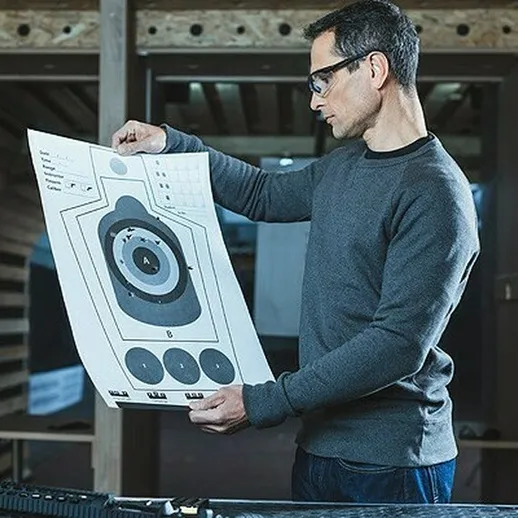 Мужчина проверяет результаты стрельбы на тире в закрытом клубе в начале утра