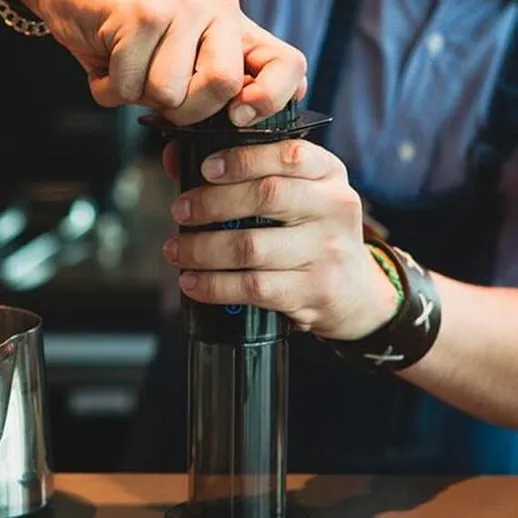 Бариста готовит кофе с помощью аэропресса в кофейне в центре города утром