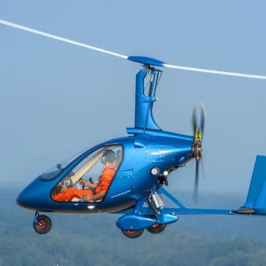 Синяя автожир, летящий над зелеными холмами в ясный солнечный день