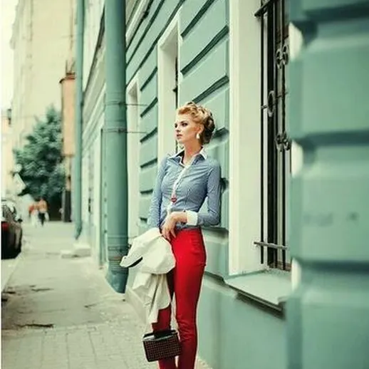 Стильная женщина в красных брюках и синей рубашке на улице города в солнечный день
