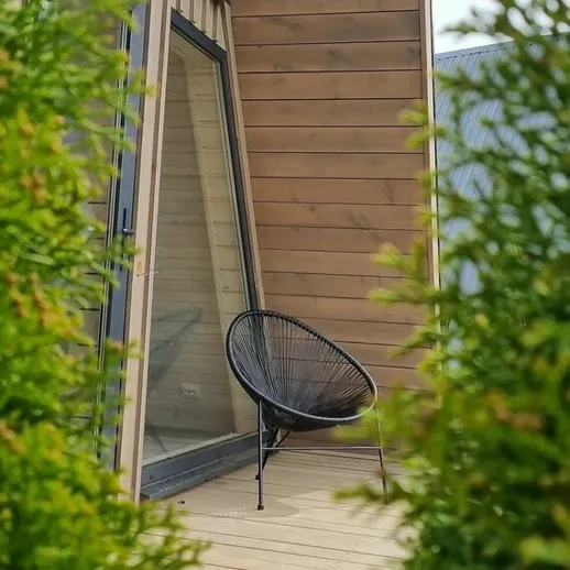 Уютный уголок на балконе с креслом и зелеными растениями в солнечный день