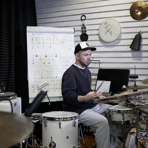 Музыкант играет на барабанах в звукозаписывающей студии во время репетиции в вечернее время