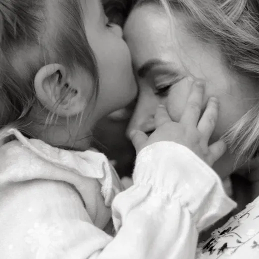 Мать и дочь нежно обнимаются, делясь теплотой на улице в мягком свете