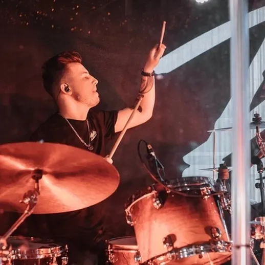 Музыкант-ударник играет на сцене в клубе во время живого выступления, атмосфера энергичного концерта