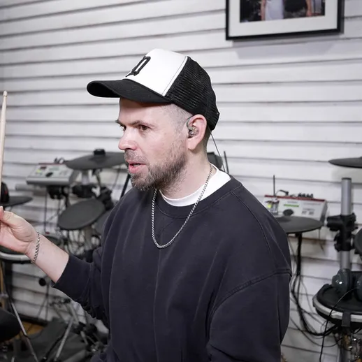 Молодой музыкант объясняет методику игры на электронных барабанах в студии