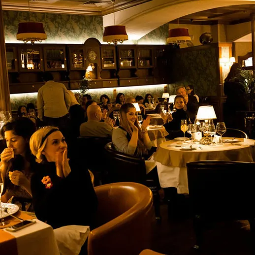 Вечерний ужин в ресторане с атмосферой уюта и живой музыкой, столы заполнены довольными гостями