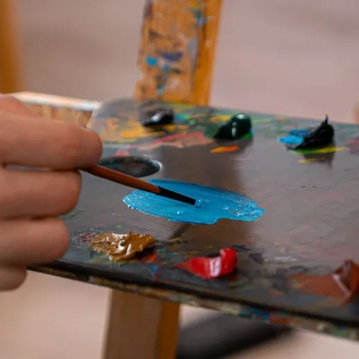 Руки художника наносят яркие цвета на палитру во время творческого процесса в студии живописи