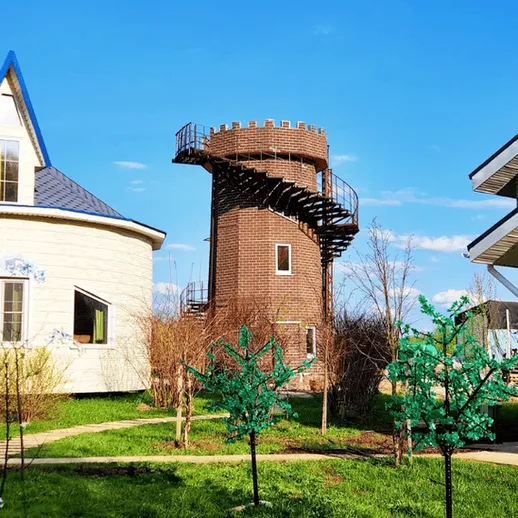 Загородный дом с башней и зелеными насаждениями в ясный день