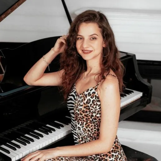 Девушка сидит за пианино и позирует для камеры в помещении