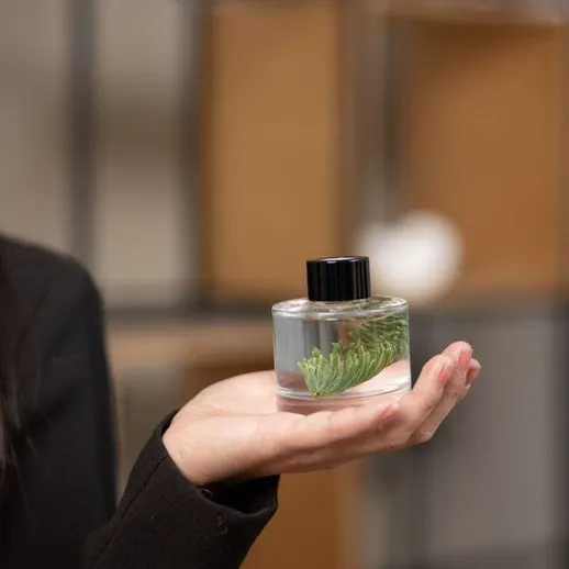 Человек держит бутылку с ароматом на фоне интерьера