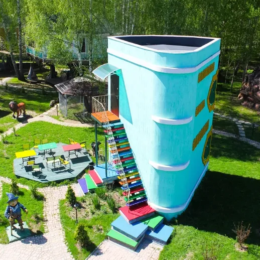 Уникальное здание в форме чашки, расположенное в живописном парке с яркими элементами и зелеными насаждениями