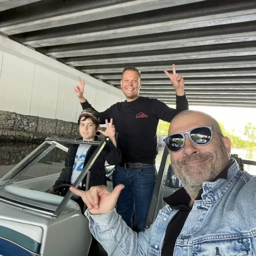 У людей веселое время на лодке под мостом с улыбками и жестами