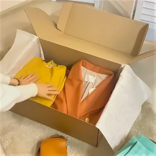 Упаковка новой одежды в коробке с аксессуарами на мягком покрытии