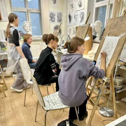 Уроки рисования в художественной школе, студенты работают над портретами в классе в вечернее время