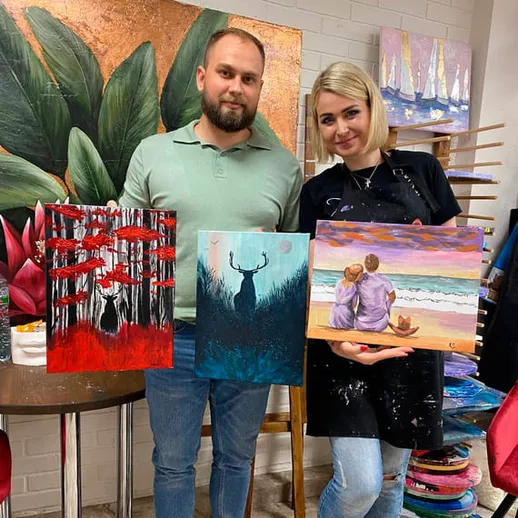 Учебный процесс по живописи в студии с участниками и их картинами на фоне