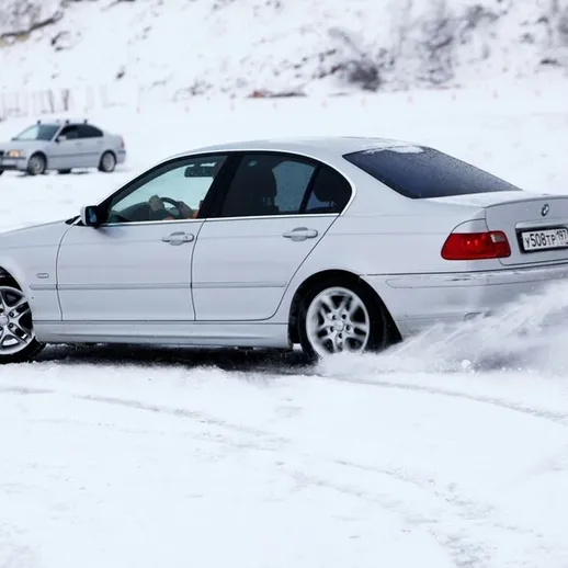 Зимняя езда на BMW в снежной местности, автомобиль скользит по снежному покрытию под зимним небом