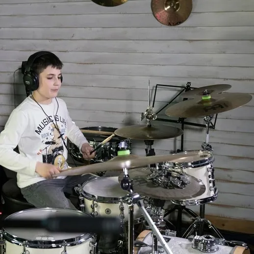 Молодой музыкант играет на барабанах в студии звукозаписи в зимнее время