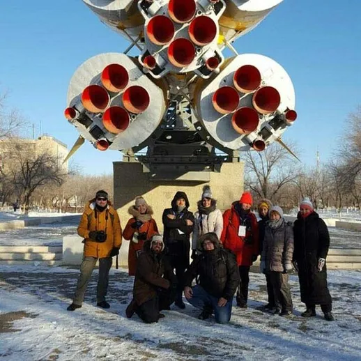 Группа людей возле ракетного двигателя на фоне зимнего дня в открытом парке космонавтики
