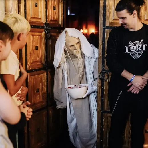 Дети наблюдают за костюмированным персонажем в темноте на аттракционе в Halloween