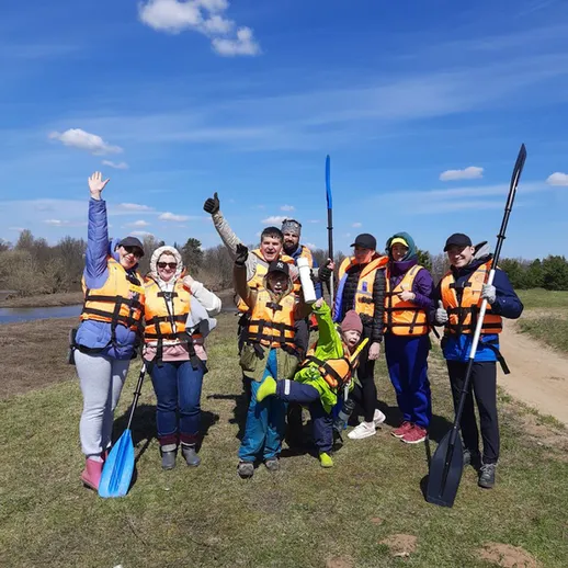 Группа людей в спасательных жилетах на берегу реки во время каякерского отдыха весной