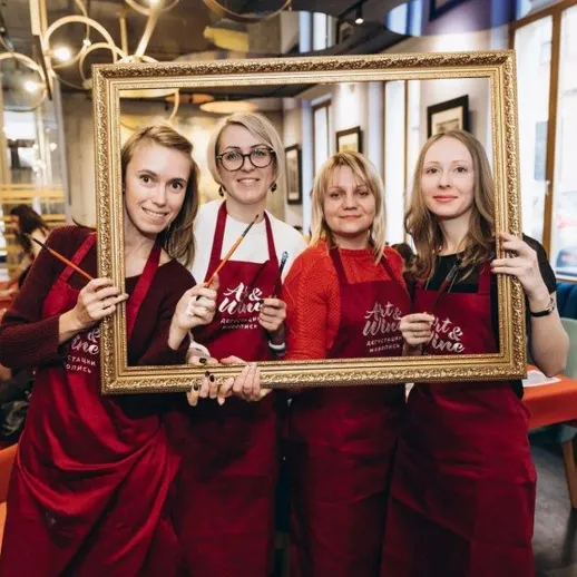 Четыре женщины позируют с рамкой в ресторане во время художественного занятия