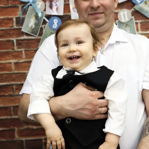 Счастливый ребенок в костюме на руках у отца на празднике в уютном кафе