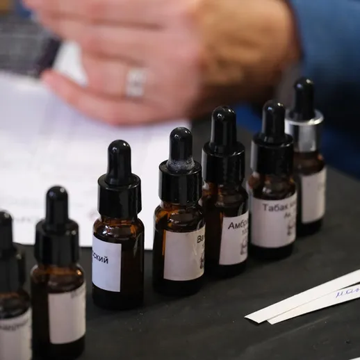 На столе расположены флаконы с маслами и готовыми смесями для ароматерапии, созданные в уютной студии в осенний день