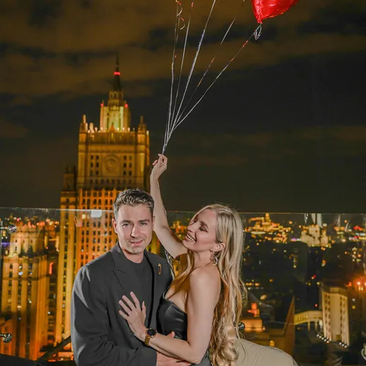 Счастливая пара на крыше с воздушными шарами на фоне вечернего города