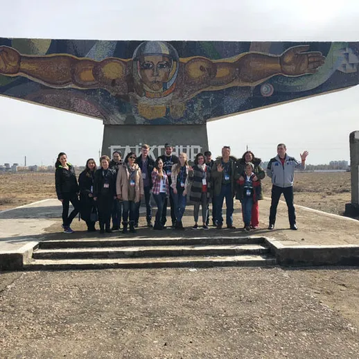 Группа людей на фоне монумента Вечного огня в памятном месте в России